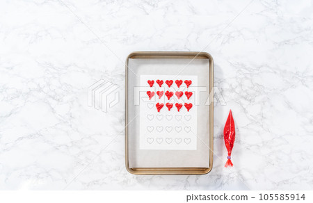 Flat lay. Piping melted chocolate from piping back over the parchment paper to make a chocolate heart. Flat lay. Piping melted chocolate from piping back over the parchment paper to make a chocolate heart. 105585914