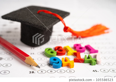 Graduation gap hat and pencil on answer sheet paper, Education study testing learning teach concept. Graduation gap hat and pencil on answer sheet paper, Education study testing learning teach concept. 105586523