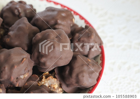 Homemade candy made from nuts and dried fruits. Some are covered in chocolate. They lie on a plate. Homemade candy made from nuts and dried fruits. Some are covered in chocolate. They lie on a plate. 105588903