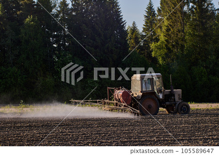 Agricultural field, crop sprayer attached to farm tractor applies herbicides to crops. 105589647
