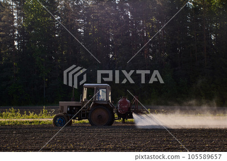 Crop sprayer with farm tractor to apply pesticides in an agricultural field. Crop sprayer with farm tractor to apply pesticides in an agricultural field. 105589657