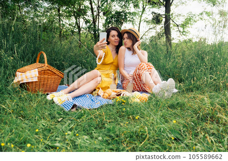 Two friends take selfie on blue blanket for an outdoor picnic Two friends take selfie on blue blanket for an outdoor picnic 105589662