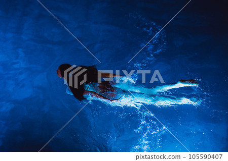 Swimmer woman in swimming pool at night on vacations, view from above Swimmer woman in swimming pool at night on vacations, view from above 105590407