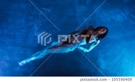 Swimmer woman in swimming pool at night on vacations, view from above Swimmer woman in swimming pool at night on vacations, view from above 105590409
