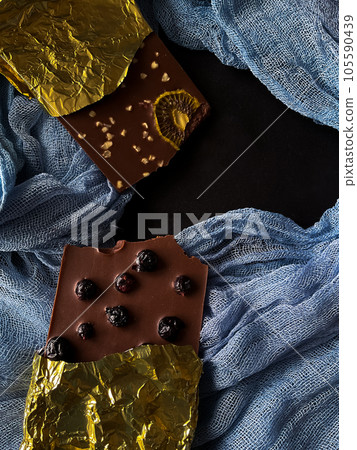 Chocolate with berries, kiwi, nuts in gold foil on blue and black background Chocolate with berries, kiwi, nuts in gold foil on blue and black background 105590439