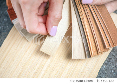 PVC edging samples close up. Women's hands hold samples of PVC edging in their hands. Components for the production of furniture, PVC edging for the processing of LMDP boards. 105590588