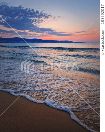 Dawn at the sea with foamy waves on the sand and colorful sky at the horizon. Sunny Beach coastline in Bulgaria. Summer and travel background 105592017