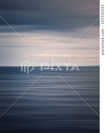 Seascape with a sailboat on the horizon, motion blur effect 105592045