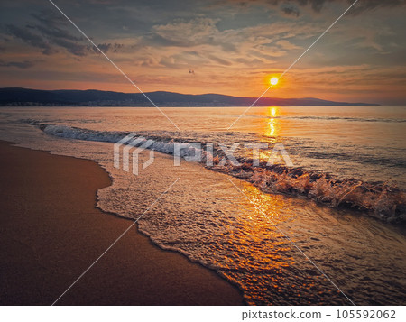Peaceful seascape, silent morning seaside with beautiful sunrise above the hills and foamy waves hitting the sand. Dawn at the sea, travel background 105592062