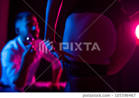 Bearded caucasian man holding an anal plug. Close-up of female buttocks in underwear. Sexual preferences of the couple. 105596467