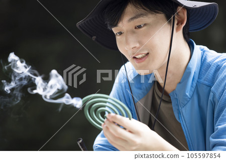 A young man lighting a mosquito coil outdoors Outdoor image 105597854