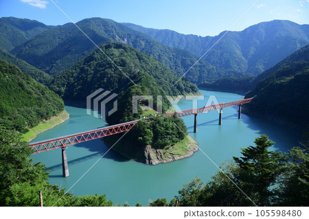 The Abt train of the Oigawa Railway Igawa Line going over the iron bridge over the meandering Oigawa River 105598480