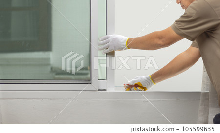 Construction worker repairing the sliding window. 105599635