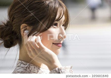 Young woman wearing wireless earphones in the city 105601640