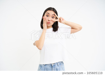 Positive korean girl, shows peace, v-sign and kissing face, posing cute against white background 105605110