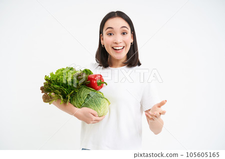 Enthusiastic vegetarian girl, holding green vegetables and smiling, recommending nutricious organic food, white background Enthusiastic vegetarian girl, holding green vegetables and smiling, recommending nutricious organic food, white background 105605165