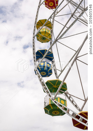 Big Ferris wheel against the sky on a cloudy day. Cabins in different colors. Place of entertainment and recreation.ferris wheel against a blue sky. High quality photo 105605546