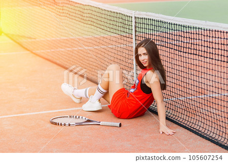 Beautiful female tennis player on tennis court. Red dress. Beautiful female tennis player on tennis court. Red dress. 105607254