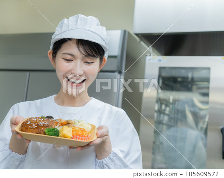 Young woman in cooking clothes standing in galley and holding lunch 105609572