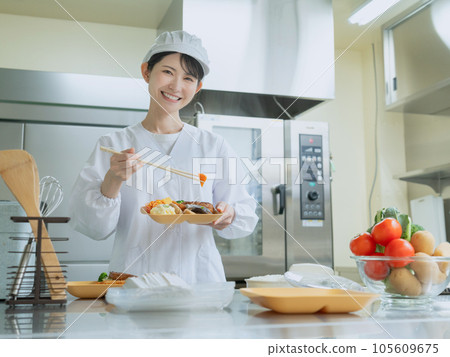 穿著做飯服的年輕女子在廚房裡打包午餐配菜 105609675