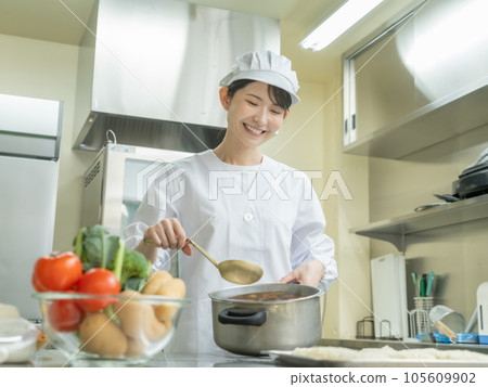 Young woman in cooking clothes making curry in the kitchen Young woman in cooking clothes making curry in the kitchen 105609902
