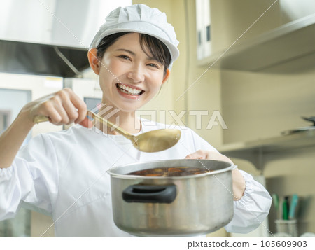 Young woman in cooking clothes making curry in the kitchen Young woman in cooking clothes making curry in the kitchen 105609903