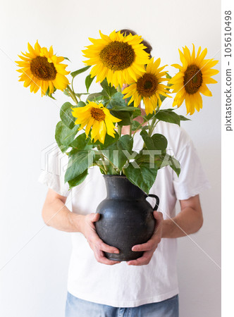 A man holds a jug with sunflowers 105610498