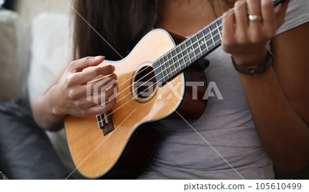 Close-up of latino female hands playing on brown ukulele 105610499