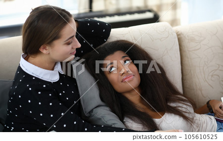 Portrait of best friends laying together on couch 105610525