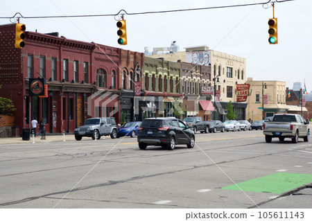 DETROIT, MICHIGAN, UNITED STATES - MAY 22, 2018: street with traffic lights, cars and low houses with stores in a suburb of Detroit DETROIT, MICHIGAN, UNITED STATES - MAY 22, 2018: street with traffic lights, cars and low houses with stores in a suburb of Detroit 105611143