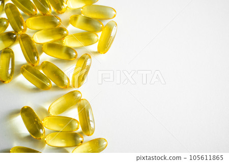 Oil filled capsules, softgel of food supplements. Fish oil, omega 3. Yellow softgels on white, copy space. 105611865