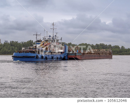 A river towboat pushing an old rusty barge down the river. Towboat and barge connected A river towboat pushing an old rusty barge down the river. Towboat and barge connected 105612046