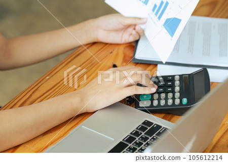 Businesswoman using a calculator to calculate numbers on a company's financial documents, she is analyzing historical financial data to plan how to grow the company. Financial concept. Businesswoman using a calculator to calculate numbers on a company's financial documents, she is analyzing historical financial data to plan how to grow the company. Financial concept. 105612214