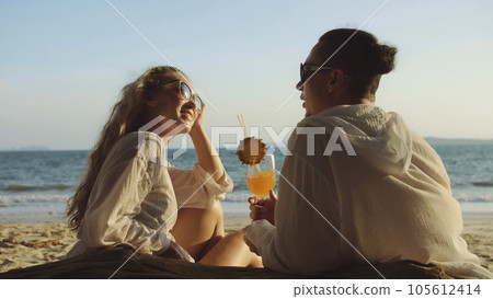 Loving couple in white dress, sunglasses, relax and drinking coc Loving couple in white dress, sunglasses, relax and drinking coc 105612414