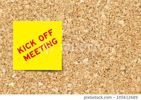 Yellow note paper with word kick off meeting on cork board background with copy space 105612689