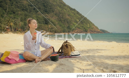 The cheerful woman in holding and eating slices of watermelon on tropical sand beach sea. Portrait attractive girl spend summer weekend. The cheerful woman in holding and eating slices of watermelon on tropical sand beach sea. Portrait attractive girl spend summer weekend. 105612777
