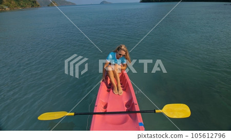 Pretty slim woman in elegant swimsuit lies in pink plastic kayak drifting on azure ocean at exotic resort upper view. Pretty slim woman in elegant swimsuit lies in pink plastic kayak drifting on azure ocean at exotic resort upper view. 105612796