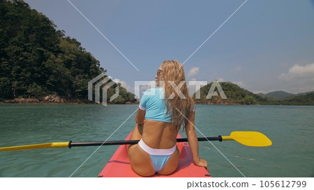 Sportive woman rows pink plastic canoe along sea water. 105612799
