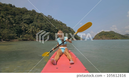 Sportive woman rows pink plastic canoe along sea water. 105612816