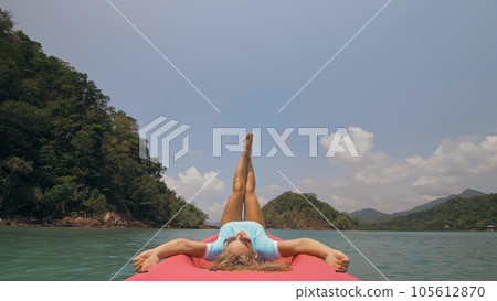 Seductive woman lifts up long legs lying on canoe on sea 105612870