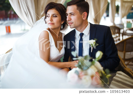 Young bride and groom in a cafe. Husband and wife hold each other's hands. Loving couple in a restaurant. 105613403