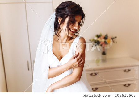 Morning of the bride. Beautiful smiling brunette bride in a white dress with a wedding bouquet in her hands. Morning of the bride. Beautiful smiling brunette bride in a white dress with a wedding bouquet in her hands. 105613603