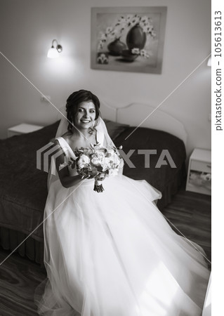 Morning of the bride. Beautiful smiling brunette bride in a white dress with a wedding bouquet in her hands. Morning of the bride. Beautiful smiling brunette bride in a white dress with a wedding bouquet in her hands. 105613613