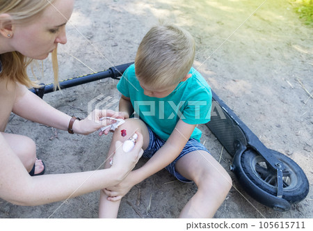 Kid fall when riding an electric scooter. Riding an e-scooter without protective gear. Increased risk of injury when using battery powered vehicles. Mom gives first aid for a knee injury 105615711