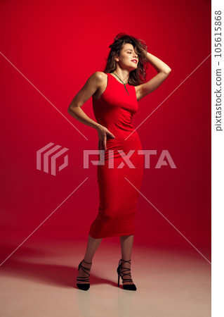 Image of attractive fashion model, dreaming girl wearing trendy clothes, red tight midi dress over burgundy background in neon light. 105615868