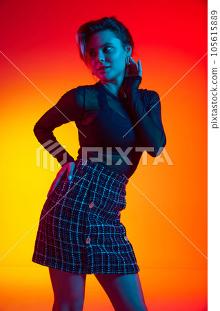 Portrait of charming woman, young fashion model wearing fashionable in transparent top posing over gradient yellow-red neon background. Portrait of charming woman, young fashion model wearing fashionable in transparent top posing over gradient yellow-red neon background. 105615889