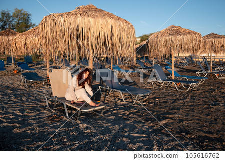 A young woman smiles at the sunrise and a new day. Holidays at the resort, on the beach. A young woman smiles at the sunrise and a new day. Holidays at the resort, on the beach. 105616762
