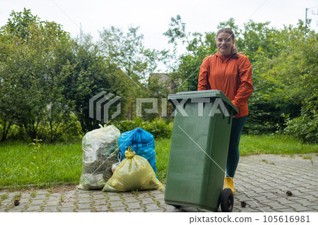 Adult woman household taking out bin to the street on rubbish day. Adult woman household taking out bin to the street on rubbish day. 105616981