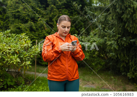 Photo of a pretty young amazing sports fat woman outdoors listening music with earphones using mobile phone. Photo of a pretty young amazing sports fat woman outdoors listening music with earphones using mobile phone. 105616983