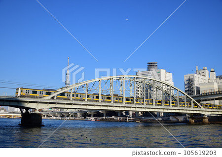 Sobu Line local train crossing the Sumida River with the Sky Tree in the background 105619203
